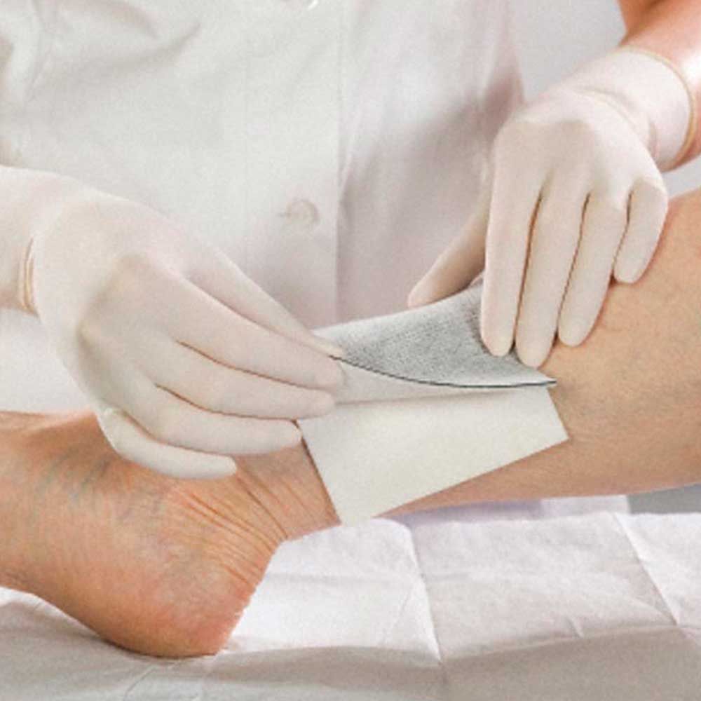 Steriler Wundverband Askina® Carbosorb wird von Händen auf die Haut aufgelegt