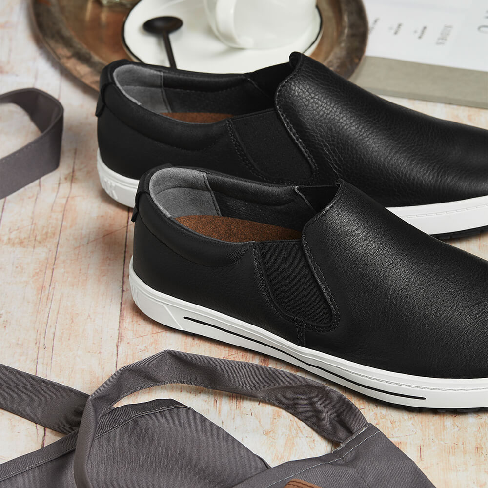 Zwei schwarze Lederschuhe mit seitlichem Gummizug und heller Profilsohle.