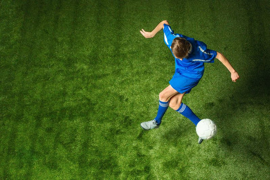 Fussballer spielt mit Ball auf Rasen ohne Verletzungen.