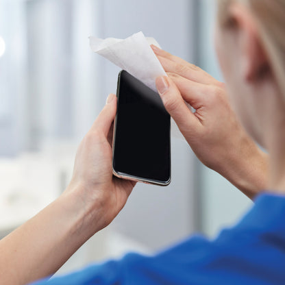 Hand reinigt ein Smartphone mit Tuch; desinfizierender Sprühnebel angedeutet