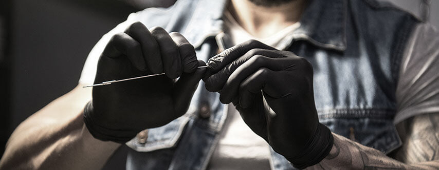 Un tatoueur porte des gants jetables en vinyle