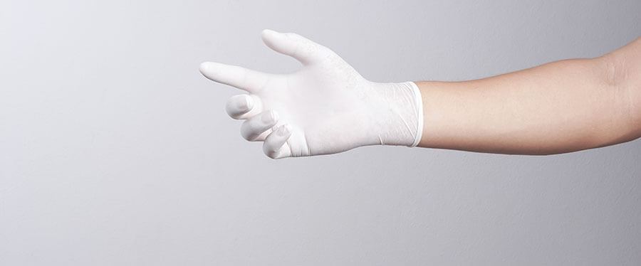 Une personne porte un gant en latex blanc