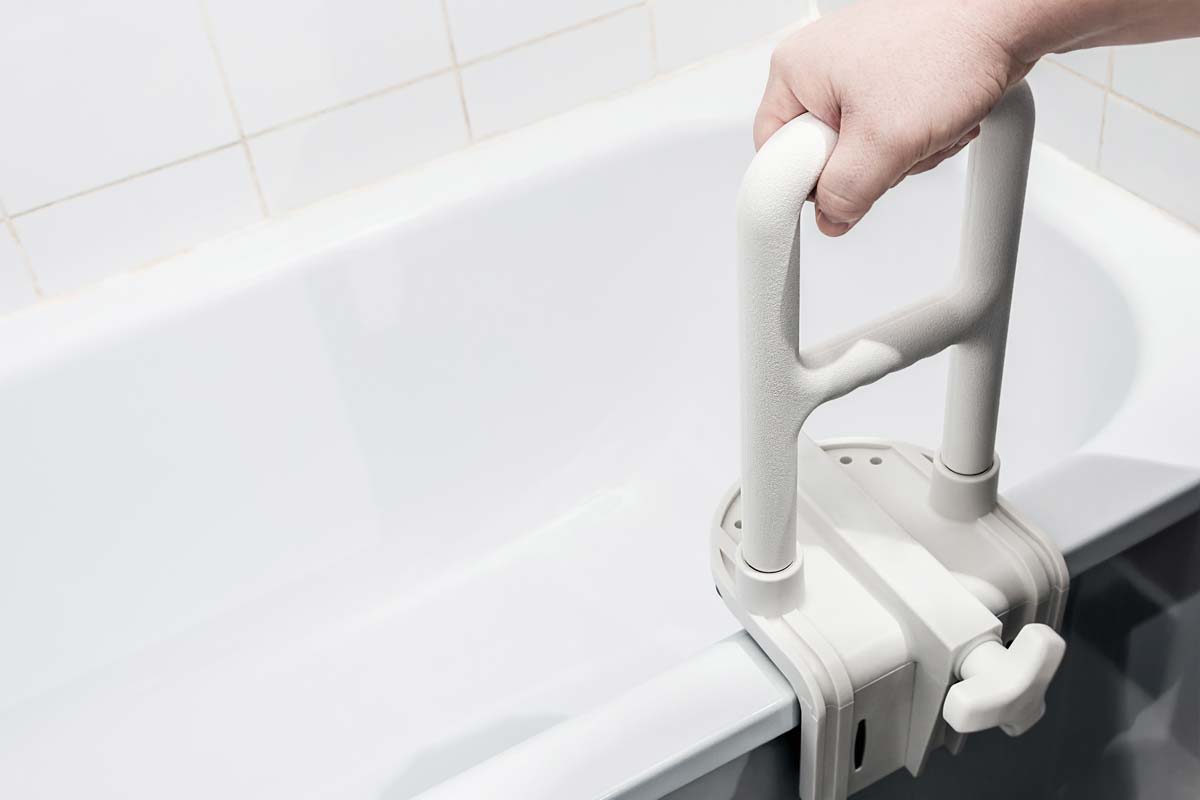 Hand hält sich an Haltegriff für eine Badewanne fest