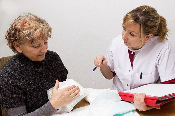 Une soignante discute des slips pour incontinence avec une patiente